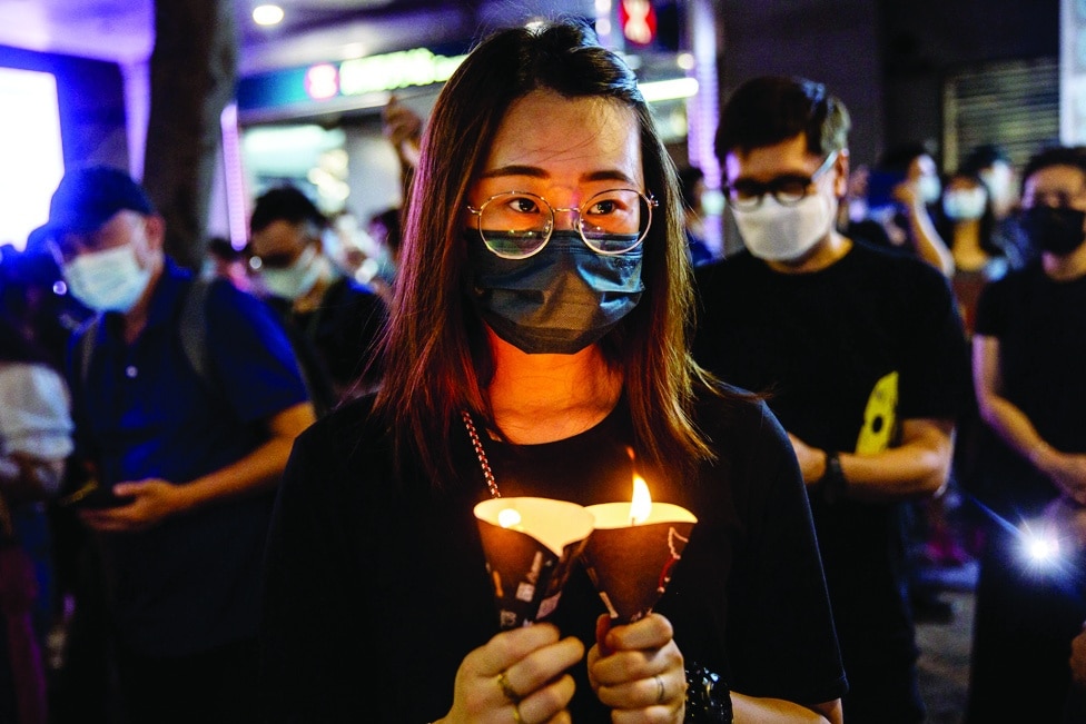 HONG KONG: File photo shows a woman holding candles in the Causeway Bay district of Hong Kong after police closed the venue where Hong Kong people traditionally gather annually to mourn the victims of China's Tiananmen Square crackdown in 1989 which the authorities have banned and vowed to stamp out any protests on the anniversary. - AFP