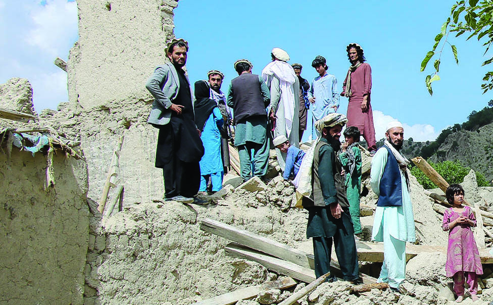 GAYAN: Afghan men talk amongst themselves as they look for their belongings amid the ruins of damaged houses after an earthquake in Gayan district, Paktika province. - AFP