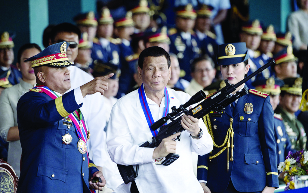 MANILA: File photo shows Philippine President Rodrigo Duterte (C) holding a Galil sniper rifle with outgoing Philippine National Police (PNP) chief Ronald dela Rosa (L) during a change of command ceremony at Camp Crame in Manila. - AFP