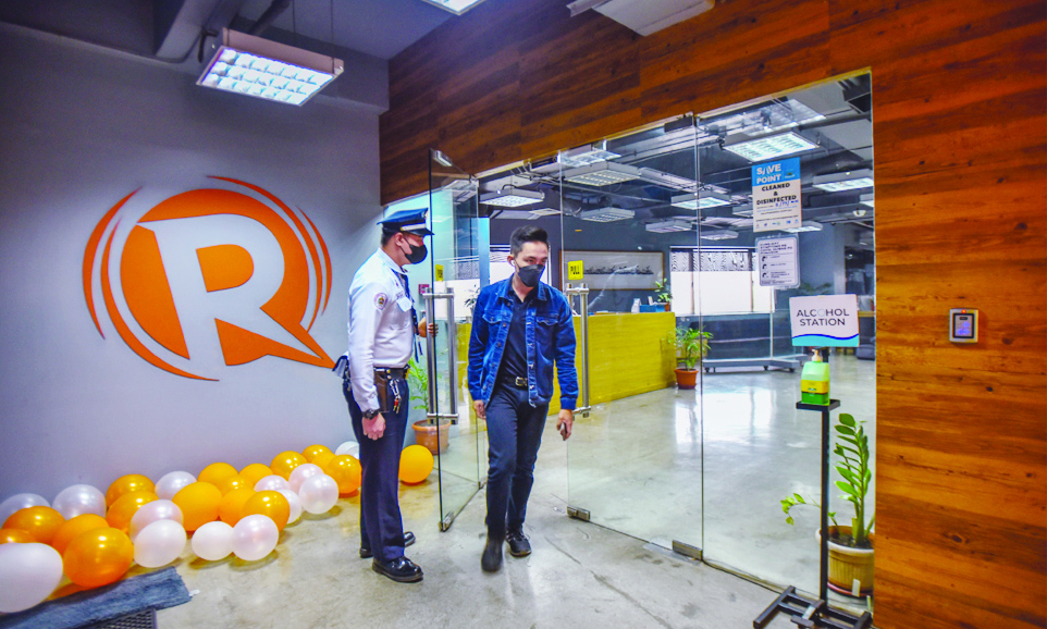 An employee of news online portal Rappler walks past the company logo at their office in Pasig City, suburban Manila on June 29, 2022. - AFP