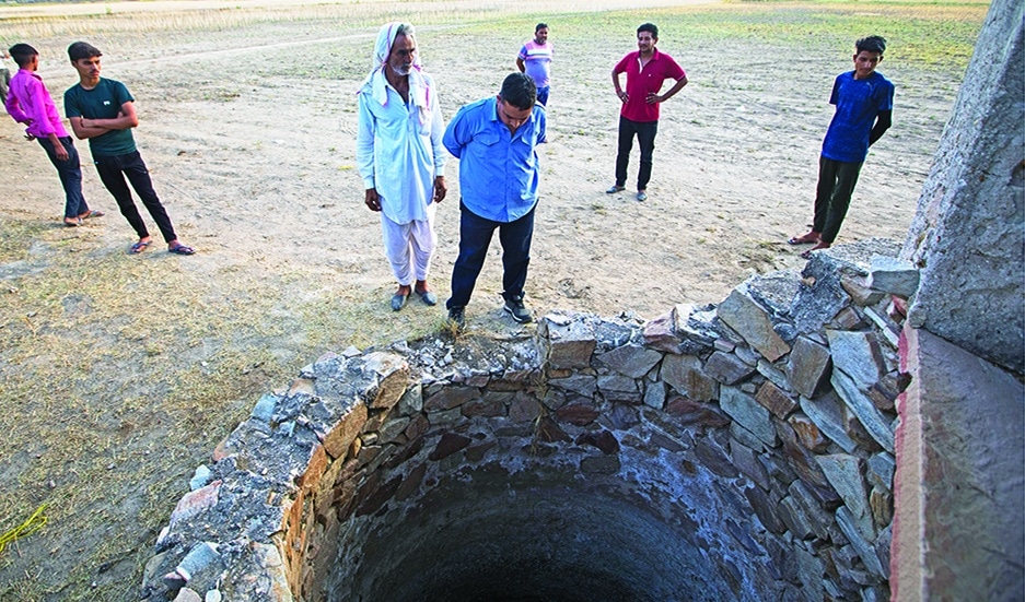 DUDU, India: Farmer Sardar Meena (center L) stands next to the well where his three married daughters and two grandchildren were found dead in a well in Dudu village of India's Rajasthan state. – AFP