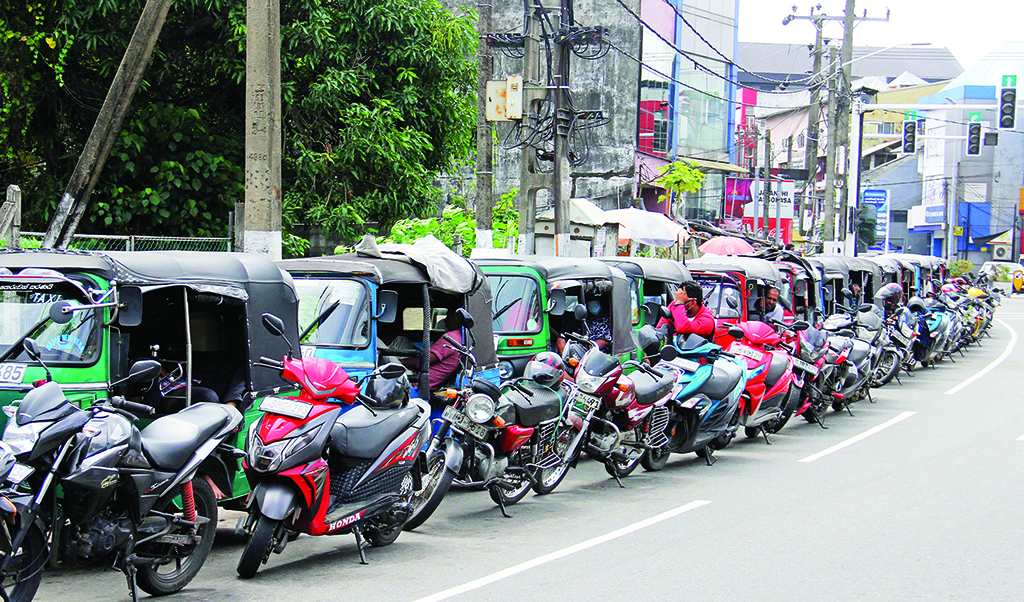 CLOMBO: Motorists queue along a street to buy fuel at a Ceylon petroleum corporation fuel station in Colombo.- AFP