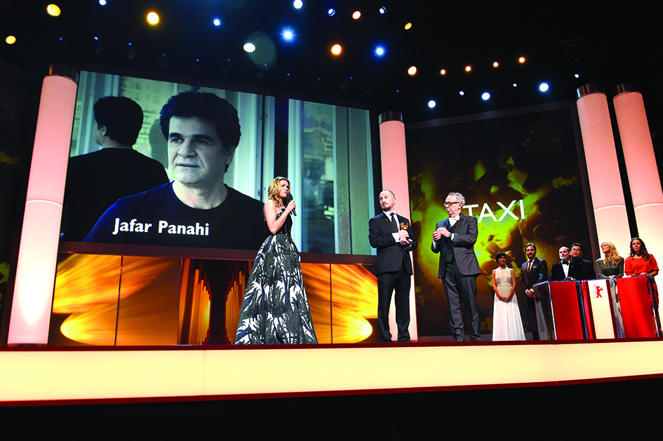 In this file photo German actress Anke Engelke (left) speaks near a giant portrait of Iranian dissident director Jafar Panahi as the President of the Berlinale International Jury Darren Aronofsky (center) holds the Golden Bear for Best Film going to Panahi for his film Taxi during the closing ceremony of the 65th International Film Festival Berlinale in Berlin.-AFP photos