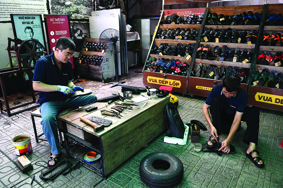 This photo shows workers making rubber sandals at a shop in Hanoi.-AFP photos