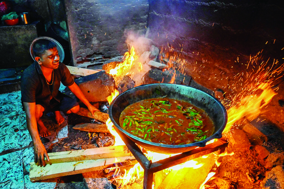 COLOMBO: In this picture taken on March 15, 2022, a man uses firewood to cook food at a restaurant. - AFP