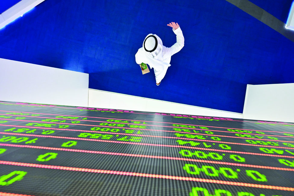 DUBAI: A trader walks by beneath a stock display board at the Dubai Stock Exchange in the United Arab Emirates. - AFP
