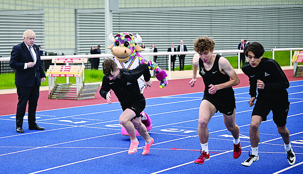 BIRMINGHAM: Britain's Prime Minister Boris Johnson (left) sets off a race between the Commonwealth Games Mascot, Perry The Bull and athletes from Burchfield Harriers on the training track beside Alexander Stadium in Birmingham, central England.- AFP