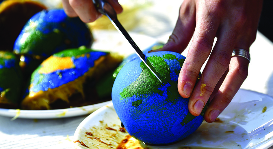 BERLIN: An environmental activist cuts an orange, painted as a globe, during an event to mark the Earth Overshoot Day in Berlin. Earth Overshoot Day marks the date when we (all of humanity) have used more from nature than our planet can renew in the entire year. - AFP
