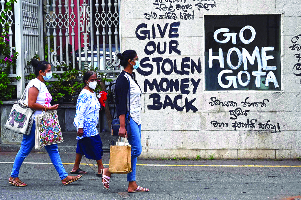 COLOMBO: Sri Lankan women walk past slogans painted on a wall against the newly elected Sri Lankan President Ranil Wickramasinghe, near the president's office residence in Colombo on July 21, 2022. - AFP