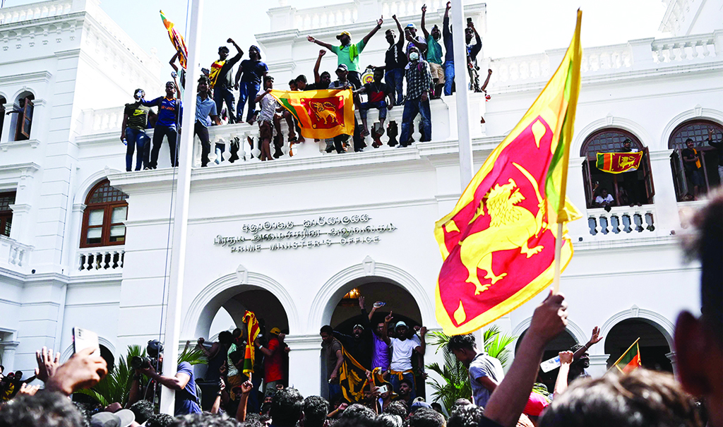 COLOMBO: Demonstrators shout slogans and wave flags during an anti-government protest inside the office building of the prime minister on July 13, 2022. - AFP