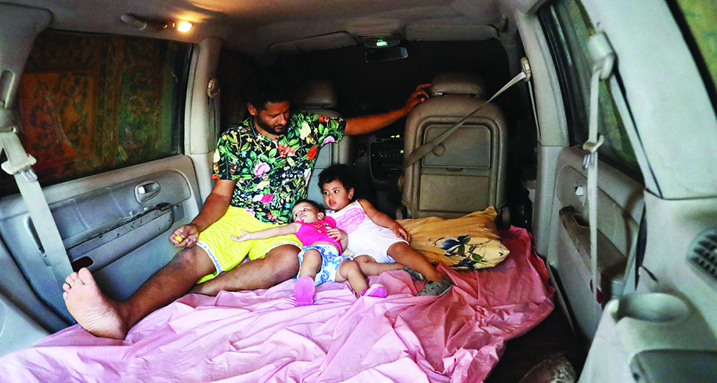 TRIPOLI: Mahmud Aguil sits with his children in the back of his air-conditioned van, parked at his home in Libya's capital Tripoli. - AFP