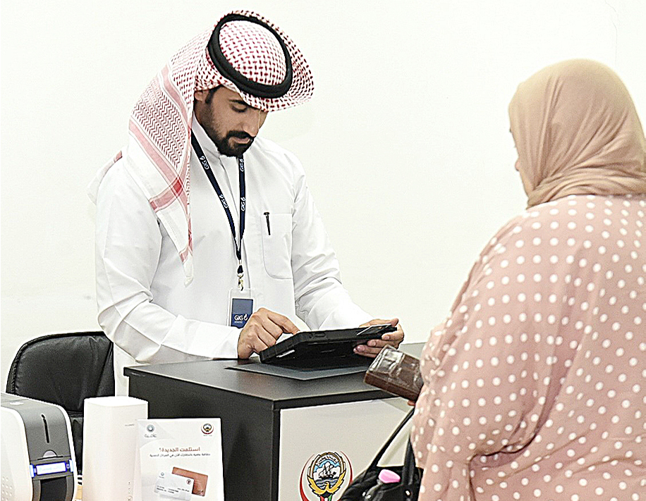 KUWAIT: A retired Kuwaiti woman receiving her Afya-3 health insurance card. - KUNA photos