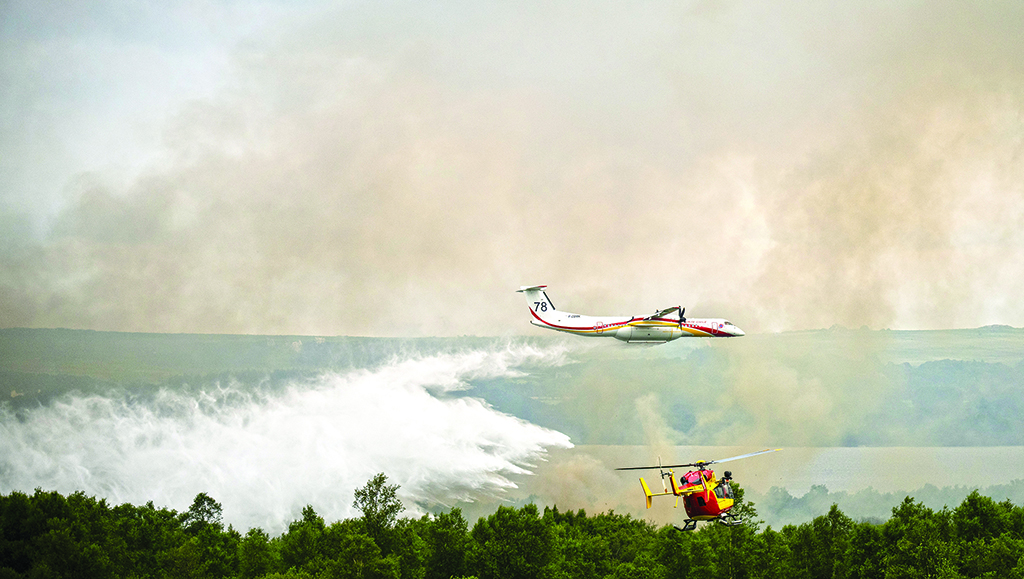 BRENNILIS, France: A De Havilland Canada Dash 8-400 MR aircraft drops water over a wildfire raging in the Monts d'Arree, near Brennilis, Brittany, on July 20, 2022. - AFP