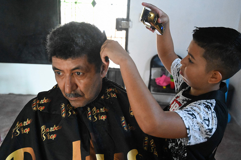 Eduardo Espinal, a 12-year-old child, cuts the hair of a client at his barbershop in Comayagua, Honduras.— AFP photos