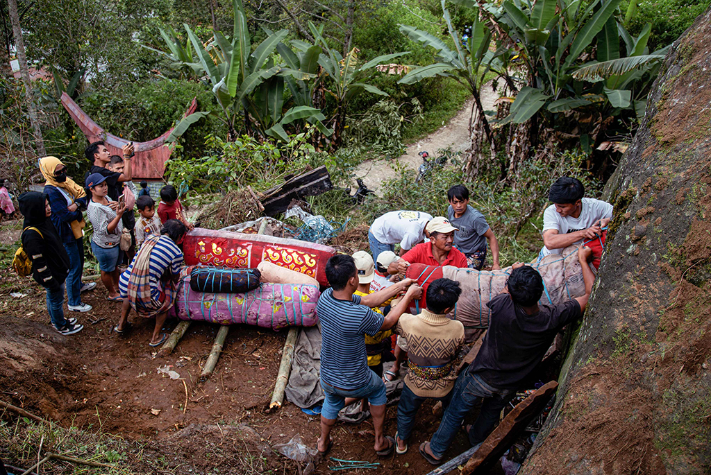 This picture shows members of the Toraja ethnic group exhuming bodies of their relatives from a community burial site (right), to be cleaned and dressed in a series of traditional ceremonies honoring the dead known as 