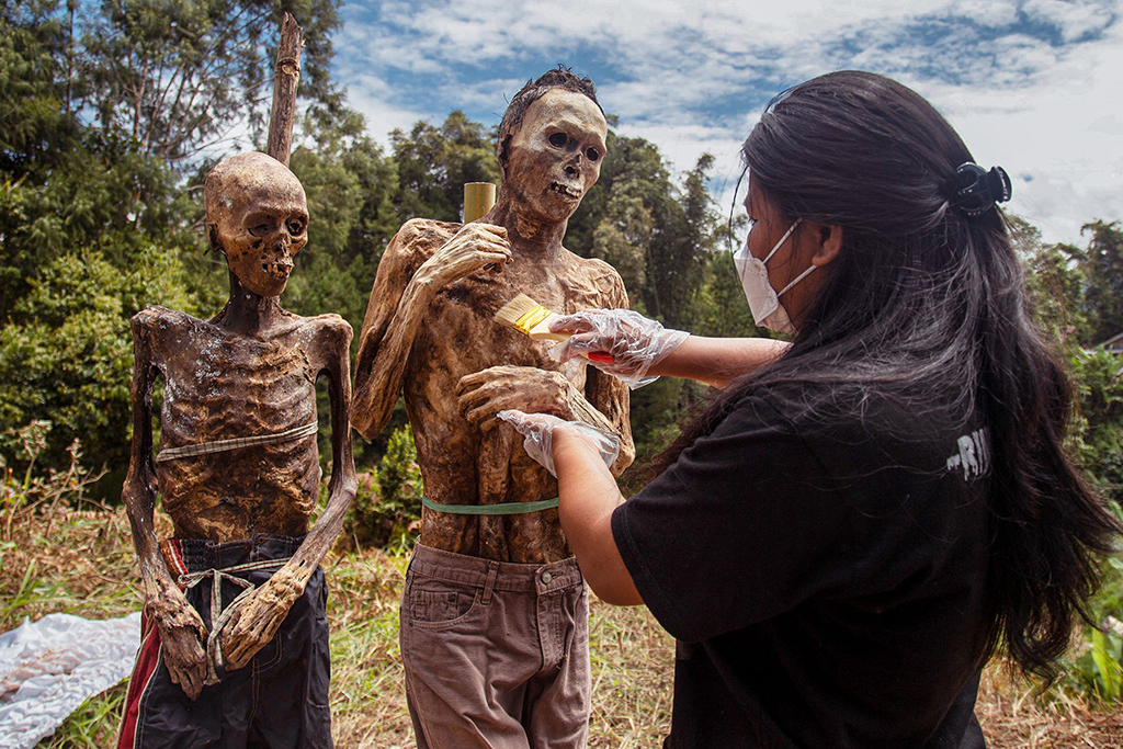A family member of the Toraja ethnic group preparing the bodies of exhumed relatives from a community burial site to be cleaned and dressed in a series of traditional ceremonies honoring the dead known as 