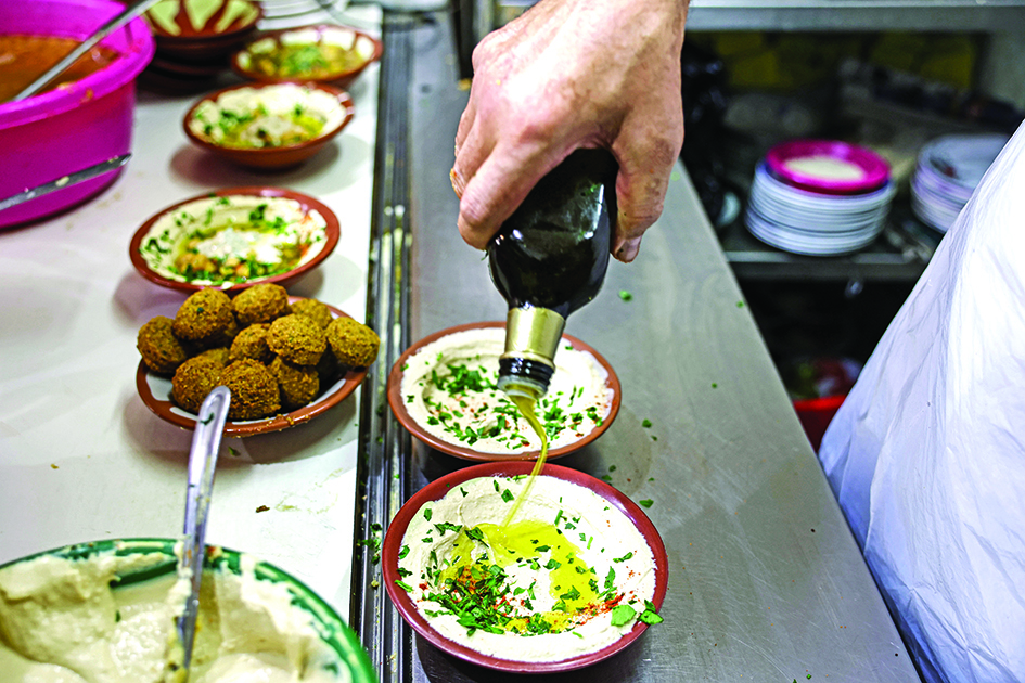 A cook prepares plates of hummus to be served to clients at a restaurant in the Old City of Jerusalem. 