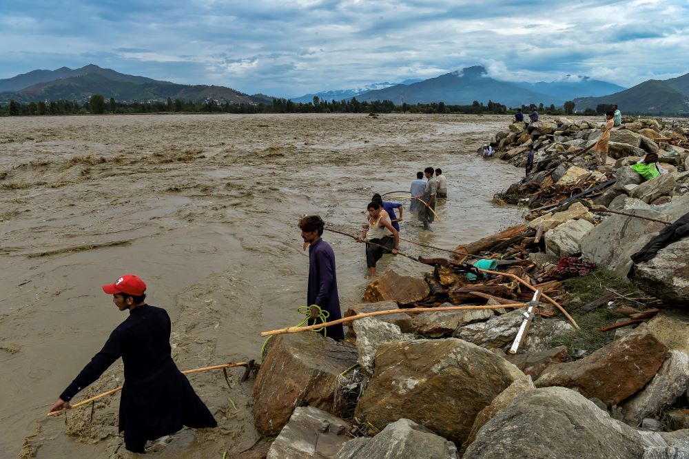 Mingora: Residents grab wood logs flowing along with the flood water following heavy monsoon rains in Mingora, a town in the Pakistan's northern Swat Valley on August 27, 2022. - AFP
