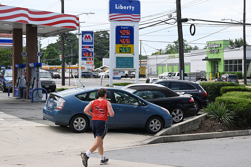 BETHESDA, United States: File photo shows a jogger runs past gas stations in Bethesda, Maryland. US retail sales held steady in July as gas prices fell and spending on automobiles dropped sharply. - AFP