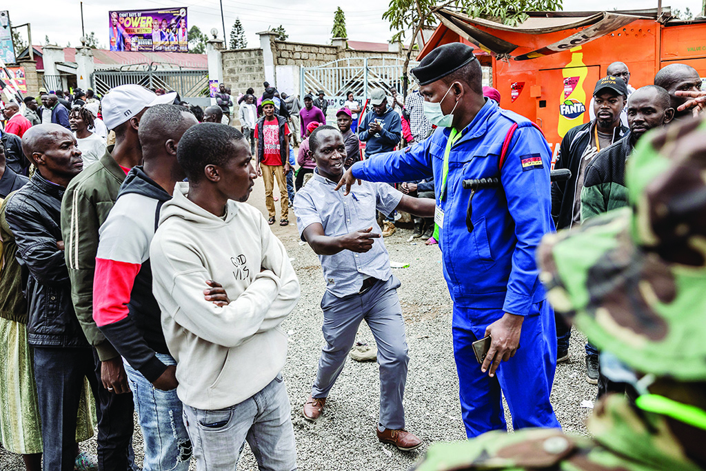 NAIROBI, Kenya:  A Kenya Police Officer pushes a man trying to gain access to a polling station while monitoring the entrance following some tensions between voters and police officers during Kenya's general election at Huruma Lions in the informal settlement of Huruma in Nairobi, Kenya. - AFP