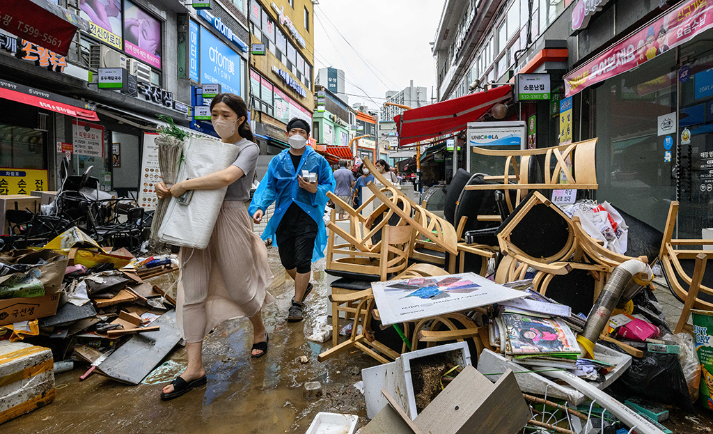 SEOUL, South Korea: Pedestrians walk past debris outside shops at the historic Namseong Market in the Gangnam district of Seoul on August 9, 2022, after record-breaking rains caused severe flooding, with at least seven people dead. – AFP