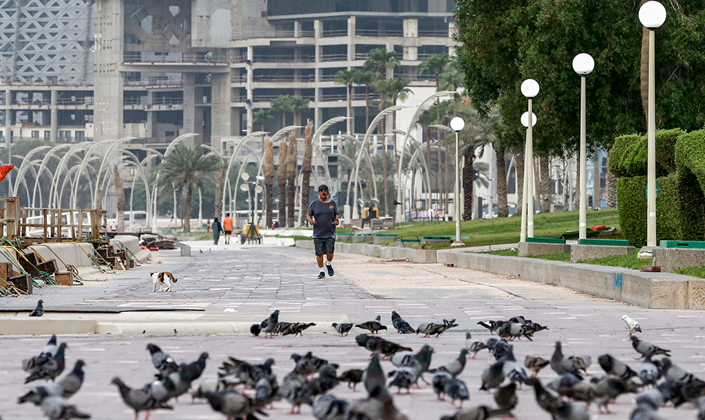 DOHA: A man jogs for exercise before pigeons feeding at Sheraton Park - West Bay in Qatar's capital Doha. Qatar on August 12 marks 100 days remaining until the start of the 2022 FIFA World Cup. – AFP