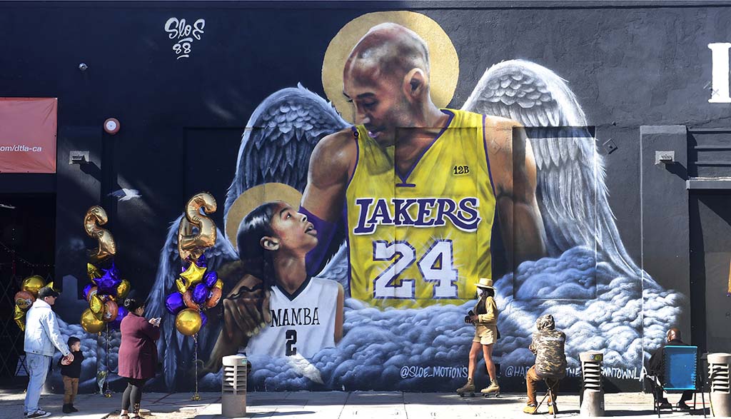 LOS ANGELES: File photo shows people gather in front of a mural of former Los Angeles Laker Kobe Bryant and his daughter Gianna, both with a set of wings, by artist sloe_motions displayed on a wall in downtown Los Angeles, California as as they mark the one-year anniversary of Kobe Bryant's death. -AFP