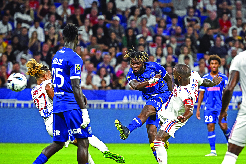 DECINES-CHARPIEU: Troyes' Malian midfielder Rominigue Kouame (center) kicks the ball past Lyon's French forward Alexandre Lacazette (right) during the French L1 football on August 19, 2022. - AFP