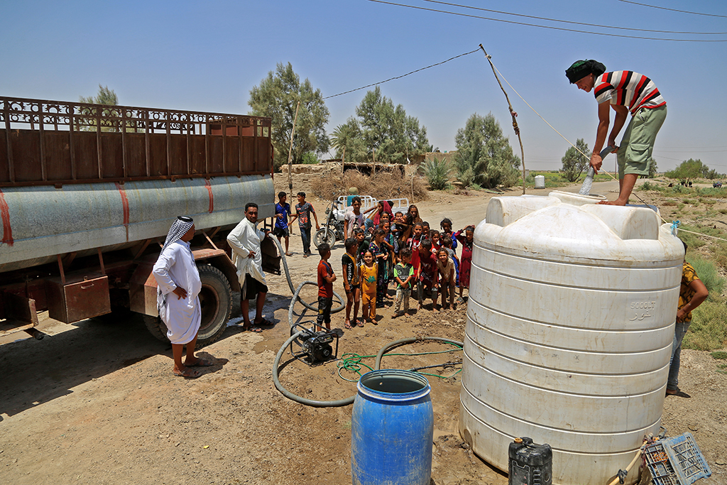 AL-AGHAWAT, Iraq: People gather to collect water from a cistern amid shortage and high temperature in this village in Diwaniya province on July 18, 2022. - AFP