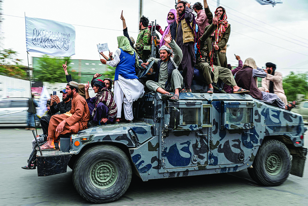 KABUL: Taleban fighters hold weapons as they ride on a humvee to celebrate their victory day near the US embassy on Aug 15, 2022. - AFP