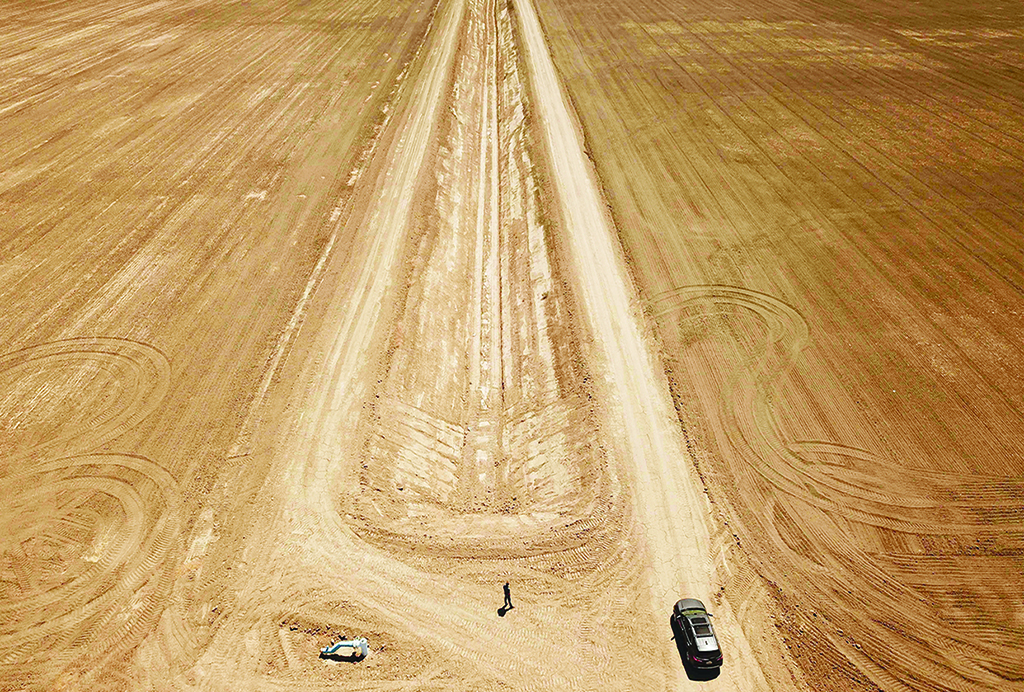 HURON, California: In this file photo taken on July 23, 2021, a farmer walks back to his car between two barren fields once sown with row crops in this town in California's drought-stricken Central Valley. - AFP