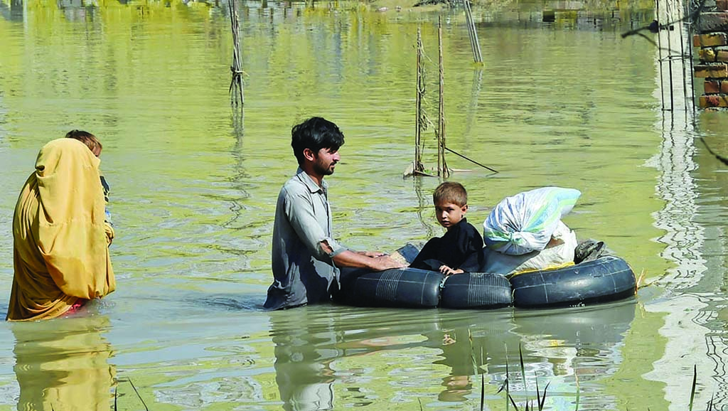 CHARSADDA, Pakistan: A family wades through a flood-hit area following heavy monsoon rains in this district of Khyber Pakhtunkhwa province on Aug 29, 2022. - AFP
