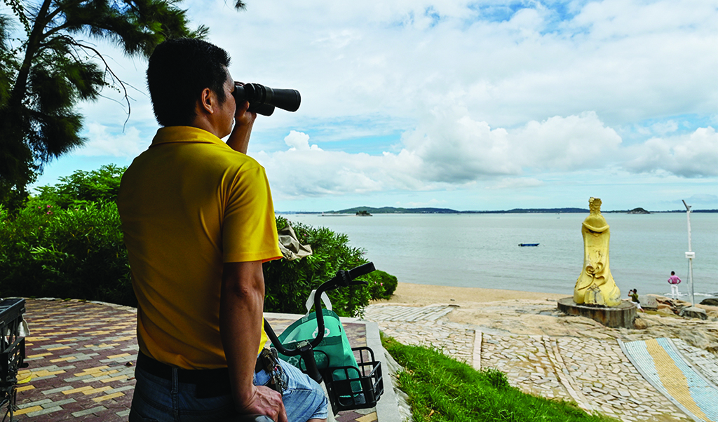 XIAMEN: A man looks through a pair of binoculars in Xiamen, across Taiwan's Kinmen Islands on August 3, 2022. US House Speaker Nancy Pelosi landed in Taiwan late on August 2, defying a string of increasingly stark warnings and threats from China that have sent tensions between the world's two superpowers soaring.- AFP