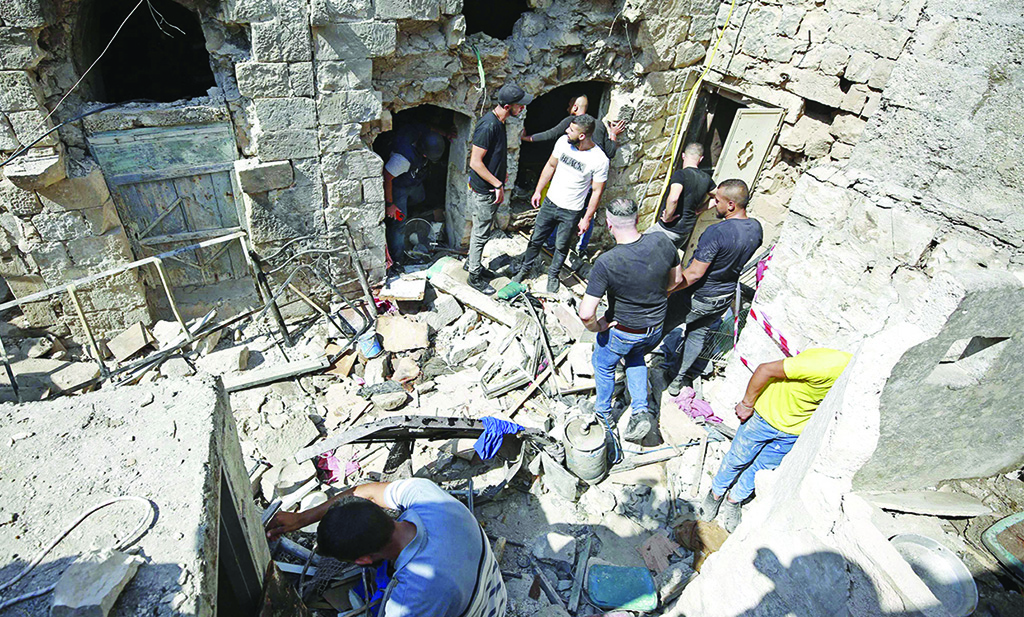 NABLUS: Palestinians search a house to evacuate the bodies of three Palestinians killed in a Zionist raid, in the West Bank city of Nablus on August 9, 2022. - AFP