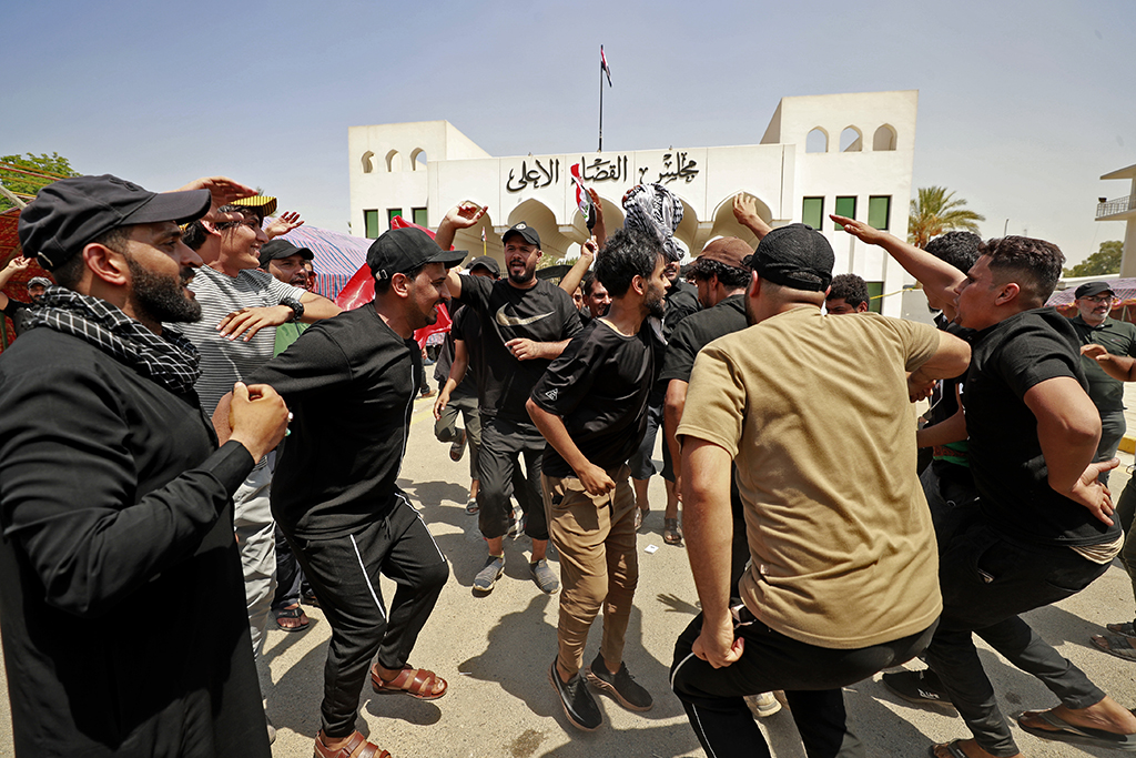 BAGHDAD: Supporters of Iraqi Muslim Shiite cleric Moqtada Sadr dance during a protest outside the headquarters of the Supreme Judicial Council, Iraq's highest judicial body, in Baghdad. - AFP