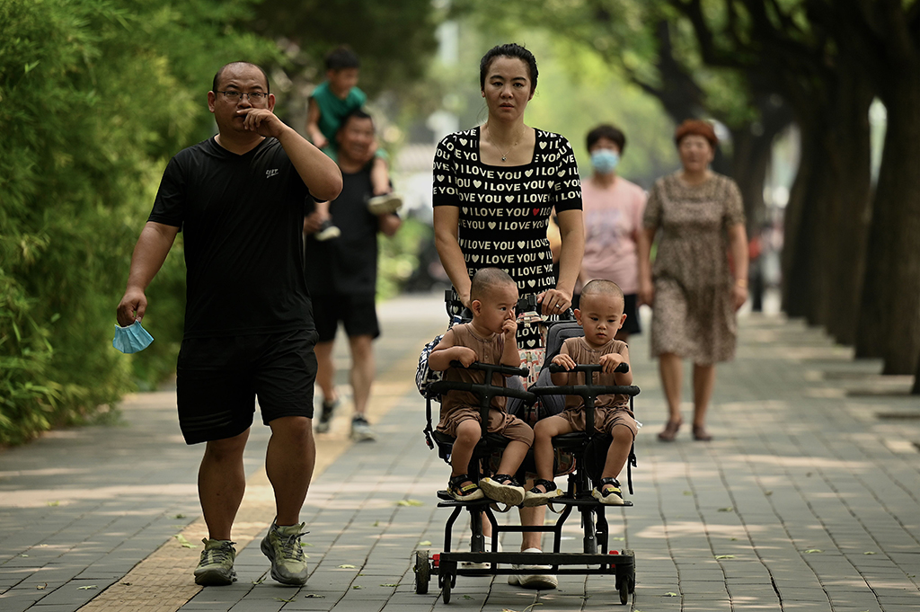 BEIJING: A woman pushes a trolley with twins along a street in Beijing on August 2, 2022. China's population will begin to shrink by 2025, officials said. – AFP