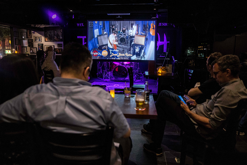 This picture shows patrons watching a band perform in a studio via a live stream, at music venue 'The Wanch' in Hong Kong. – AFP photos