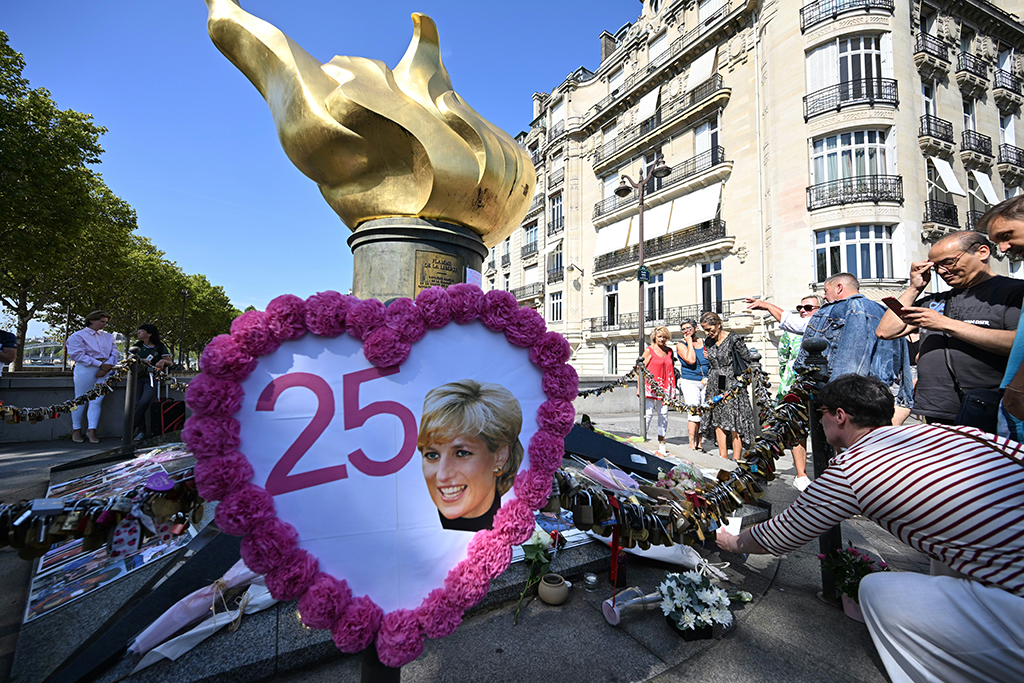 A woman leaves a note as people gather to commemorate the 25th anniversary of the death of Lady Diana Spencer. - AFP