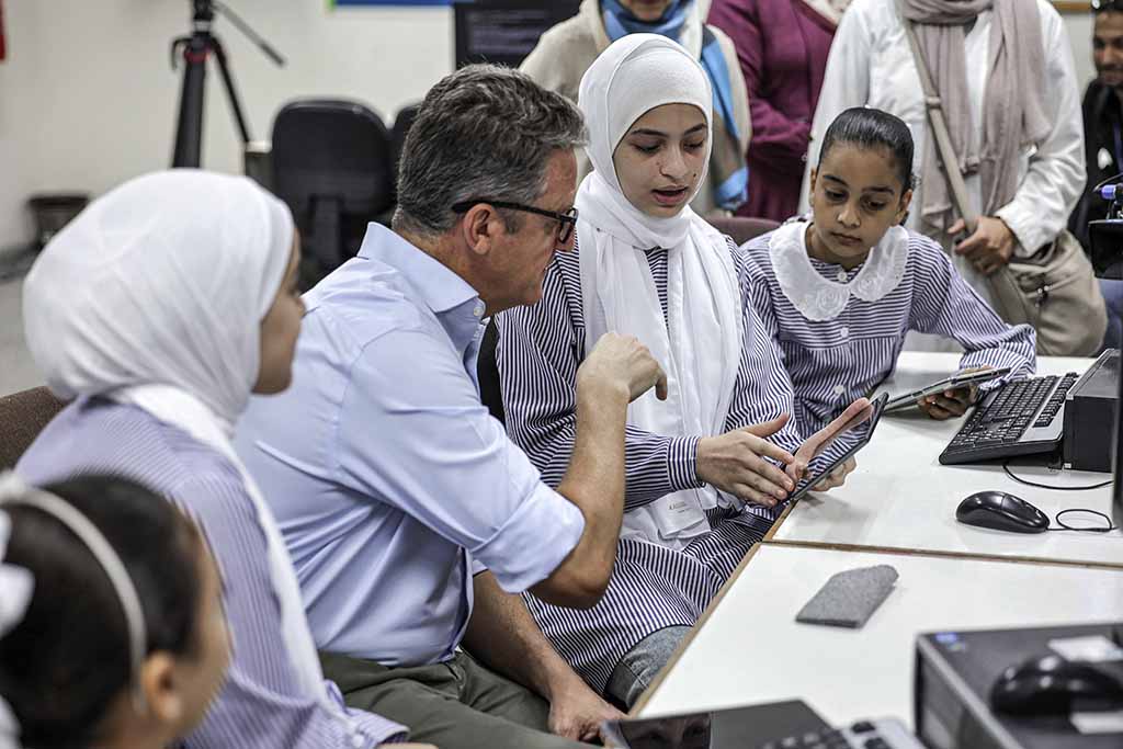 Thomas White, director of United Nations Relief and Works Agency for Palestine Refugees (UNRWA), instructs students at an UNRWA school on how to use one of the new electronic tablets in class, in Gaza City.
