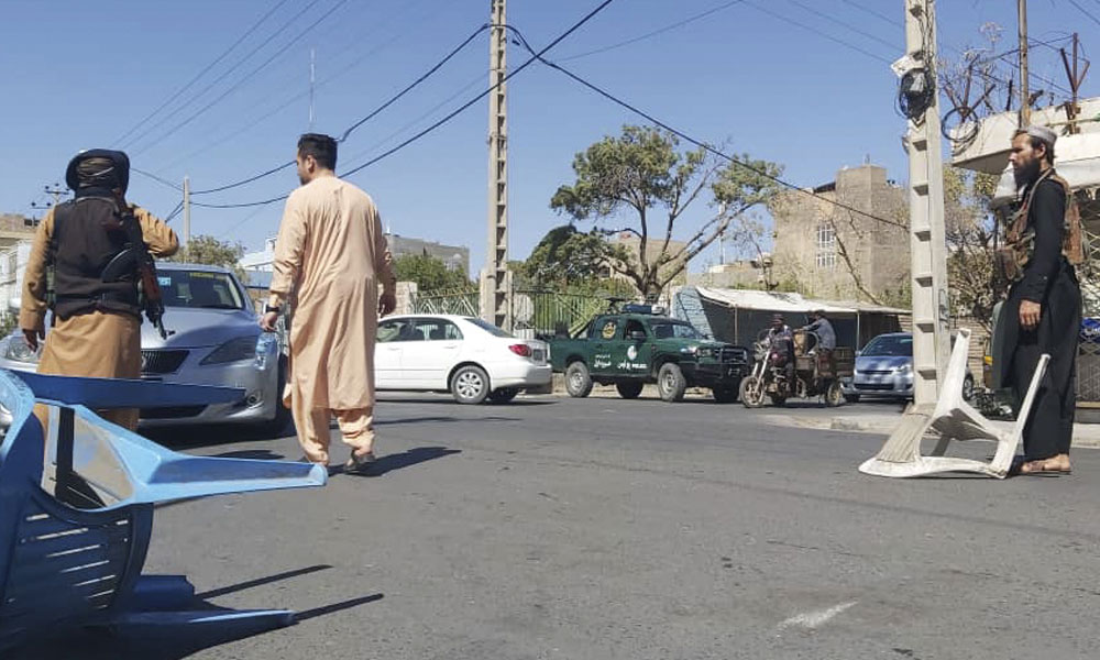 Taliban fighters block a road after a blast during the Friday prayer in Gazargah mosque, in Herat