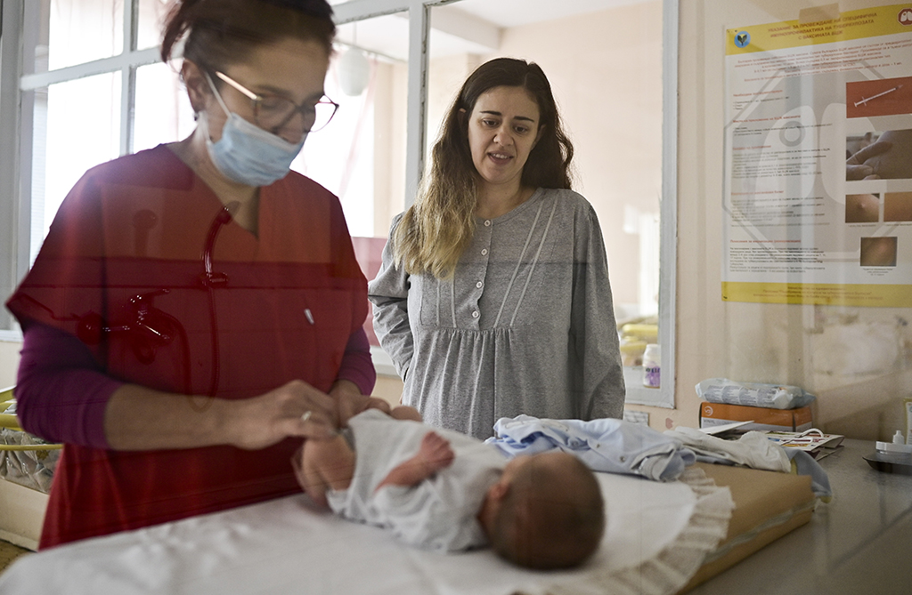 GABROVO, Bulgaria: A nurse taking care of a newborn boy in front of his mother in the maternity ward in the Gabrovo hospital. - AFP