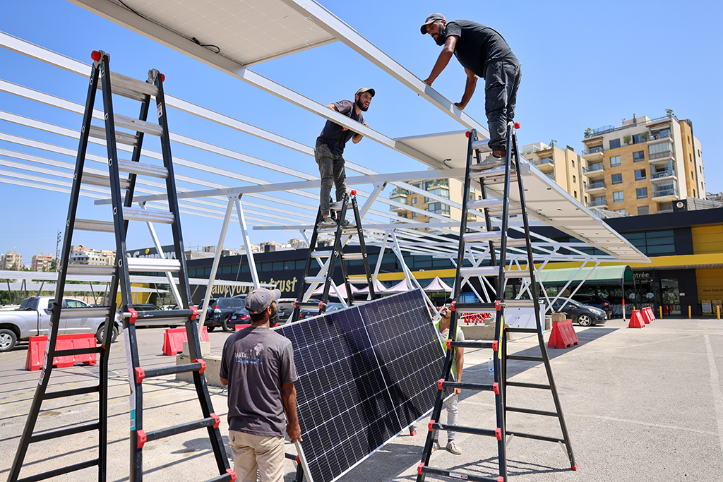 BYBLOS, Lebanon: Workers install new solar panels as shades above vehicles in the parking garage of a shopping mall in the city of Byblos in northern Lebanon on August 26, 2022. -  AFP