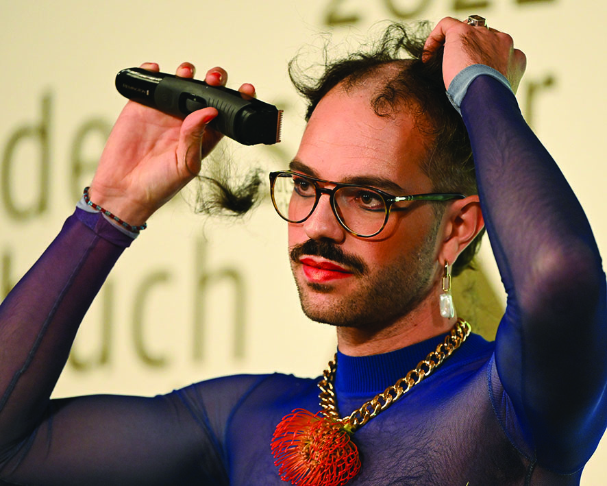Swiss writer Kim de l'Horizon shaves over their hair in solidarity with the protesting women of Iran having received the German Book Prize in Frankfurt.— AFP