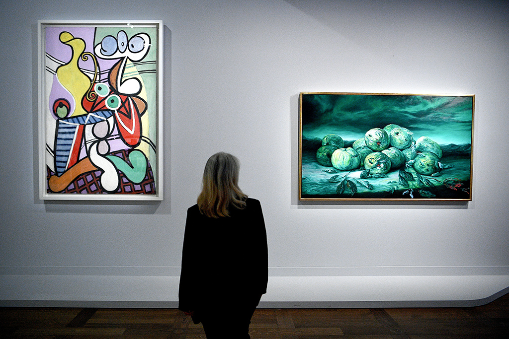 A visitor looks at artworks titled 'Grande Nature morte au gueridon' (Great Still life on pedestal) (left) by artist Pablo Picasso and 'Burlesque' (right) by artist Glenn Brown as part of the 'Les choses - Une histoire de la nature morte' (Things - A History of Still Life) exhibition at the Louvre museum in Paris.- AFP