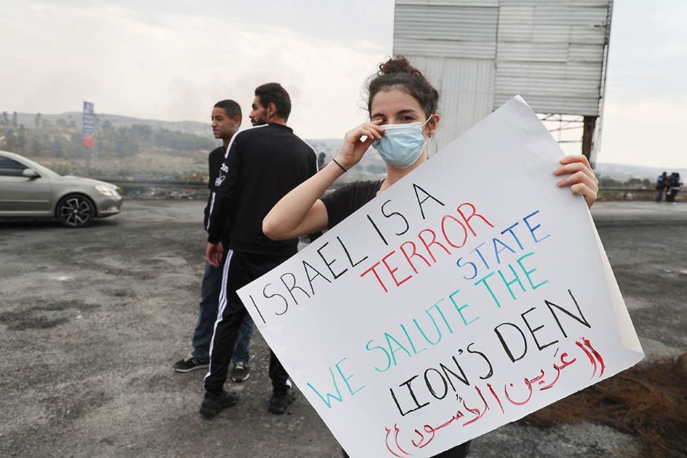 NABLUS: A Palestinian protester lifts a placard during a demonstration demanding the opening of roads near the settlement of Shavei Shomron in the occupied West Bank on Oct 21, 2022. - AFP 