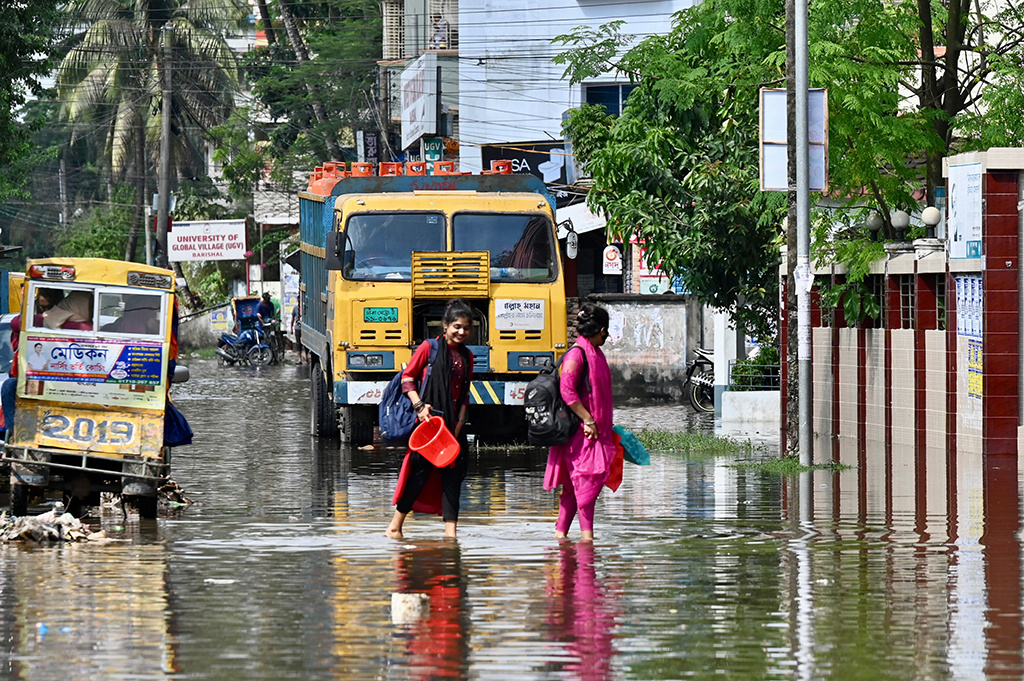 BARISAL, Bangladesh: Women wade through a waterlogged street following cyclone Sitrang, in Barisal. – AFP
