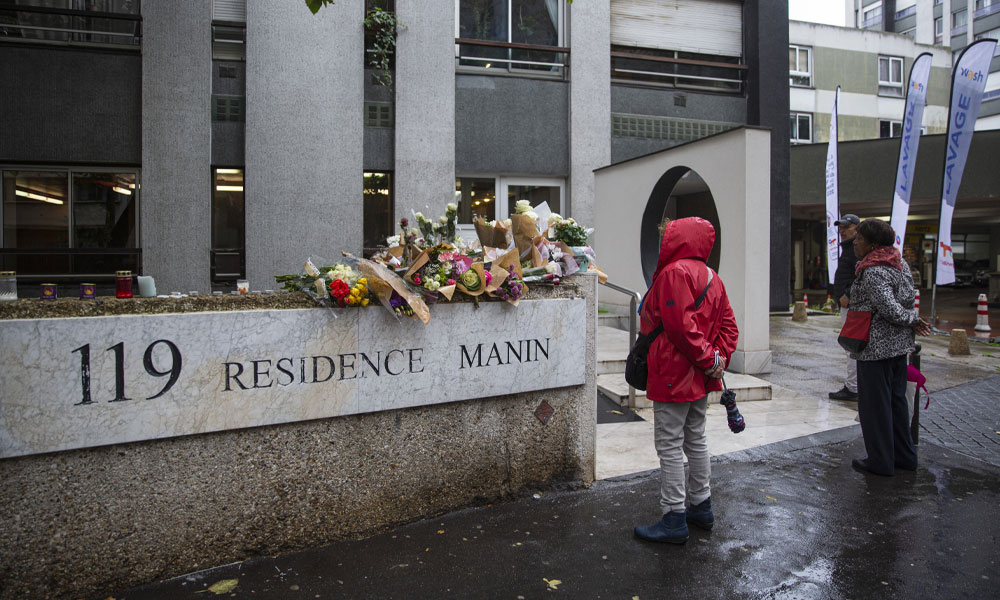 Members of the public stand in front of bunches of flowers displayed outside the building in Paris on October 17, 2022, where lived a 12-year-old schoolgirl, named Lola, three days after her body was discovered in a trunk in the 19th district.