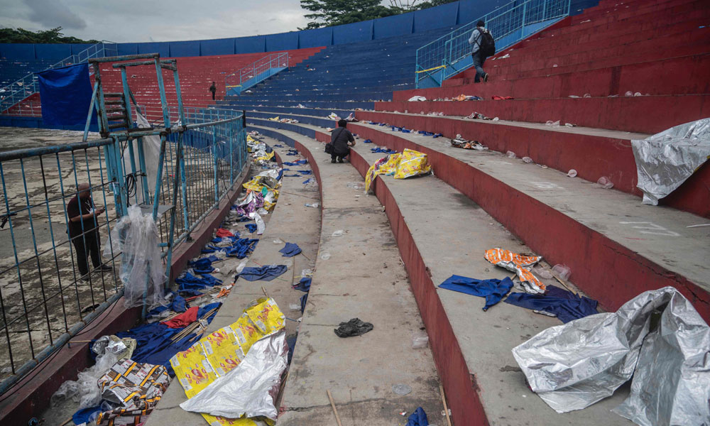 People walk amongst debris in the stands at Kanjuruhan stadium days after a deadly stampede following a football match in Malang, East Java on October 3, 2022.