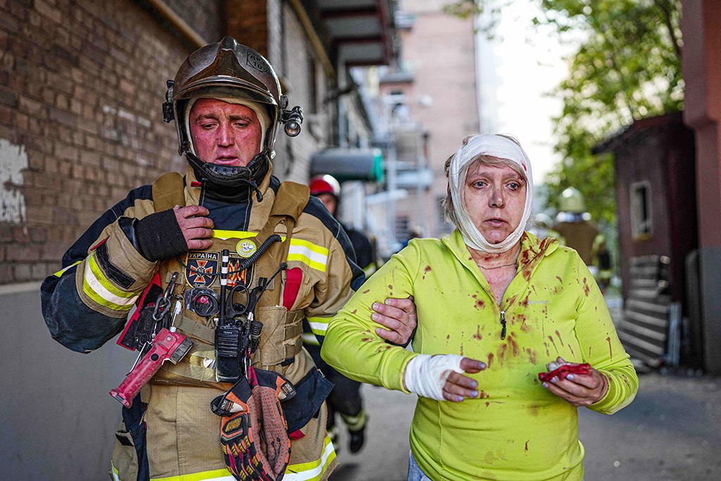 KYIV: A rescuer helps an injured woman on Oct 10, 2022 after several strikes hit the Ukrainian capital amid Russia's invasion of Ukraine. - AFP