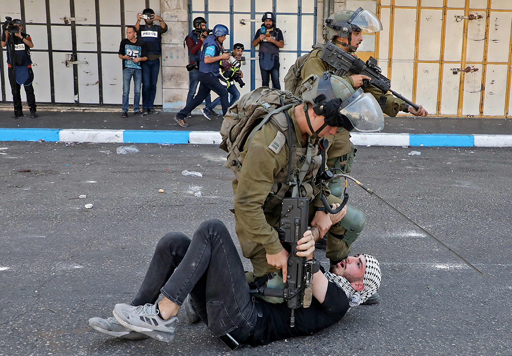 HEBRON: Zionist soldiers scuffle with a Palestinian during clashes in this flashpoint city in the occupied West Bank on Oct 20, 2022. - AFP